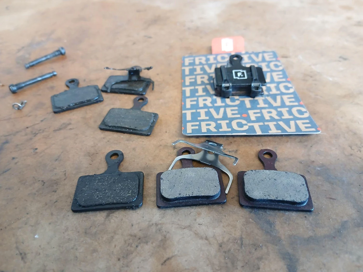 Old and new disc brake pads on the workshop bench